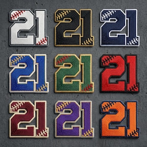 May include: Nine embroidered patches shaped like the number 21, each featuring baseball-style red stitching details. The patches come in white, black, navy, blue, green, red, maroon, purple, and orange, all with contrasting borders.