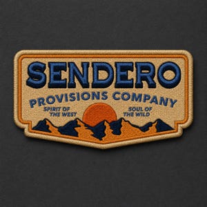 May include: A rectangular embroidered patch with rounded corners featuring a tan background, dark blue text reading SENDERO PROVISIONS COMPANY, and the phrases SPIRIT OF THE WEST and SOUL OF THE WILD flanking an orange sun over dark blue mountains.