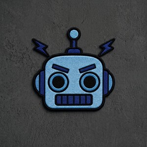 May include: An embroidered patch featuring a light blue robot head with dark blue accents. The robot has a square face, round black eyes, a rectangular mouth, and two lightning bolt shapes extending from the sides of its head.