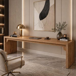 May include: A long, light brown wooden desk with a gold lamp, books, and a laptop. The desk is in a modern room with a painting and a chair. The desk is approximately 72 inches long.