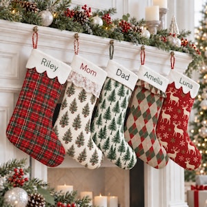Könnte beinhalten: Fünf personalisierte Weihnachtsstrümpfe hängen in einer Reihe. Der erste ist rot-grün kariert, der zweite hat ein Weihnachtsbaum-Muster mit Spitze, der dritte ein grünes Baummuster, der vierte ein Rautenmuster und der fünfte ist rot mit weißen Hirschen.