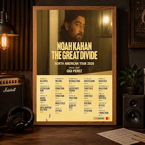 May include: A framed poster for Noah Kahan's "The Great Divide" North American Tour 2026, featuring Gigi Perez. The poster is in a wooden frame and includes a list of tour dates and venues. The image is set against a dark, wooden background.