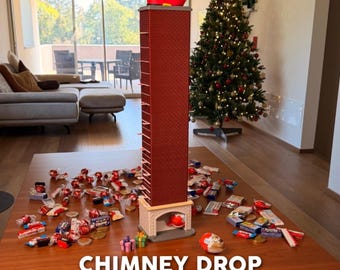 May include: A tall, red brick-patterned modular chimney advent calendar with a Santa Claus figure stuck in the top. The base features a fireplace opening, and the structure is surrounded by various wrapped sweets and chocolates on a wooden table.
