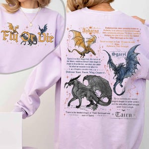 Puede incluir: Una sudadera lila con temática de dragones. La parte delantera presenta el texto "Fly or Die" con ilustraciones de dragones. La parte trasera muestra ilustraciones y texto de dragones, incluyendo los nombres "Andarna", "Sgaepl" y "Tairn".