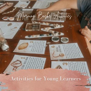 May include: Educational materials for a morning basket activity featuring printed cards with illustrations and text about worm life cycles, a clear glass jar with white fragments, and a zigzag line of small stones on a wooden table surface.