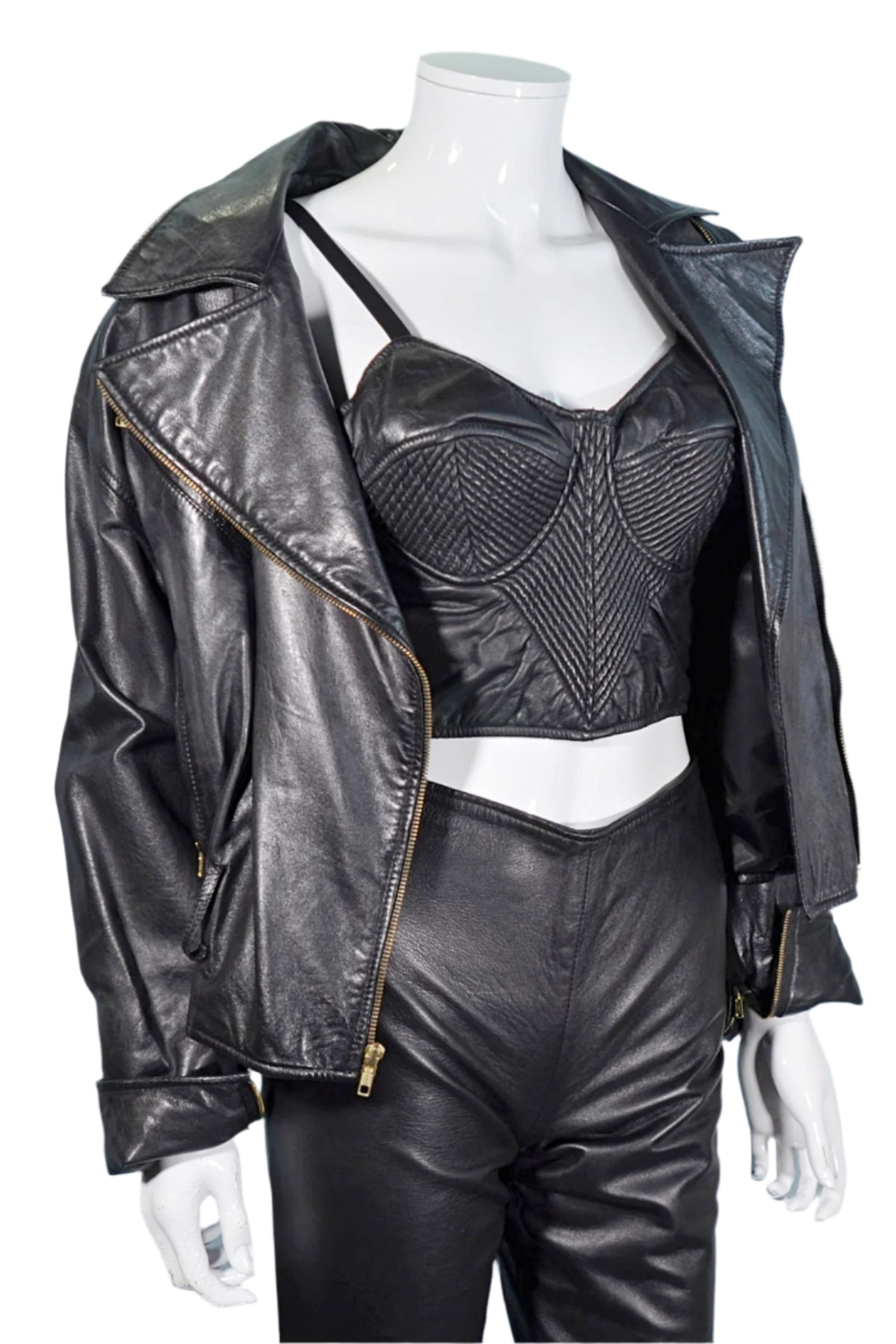 May include: Black leather jacket with a notched collar and a zip closure. The jacket is paired with a black leather bustier and matching leather pants. The bustier has a quilted design. The outfit is displayed on a white mannequin.
