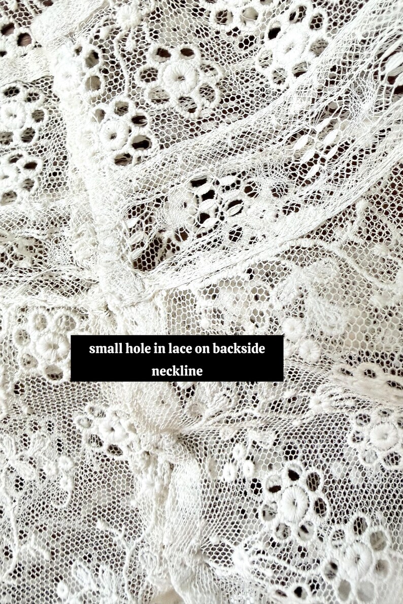 May include: Close-up of white lace fabric with a delicate floral pattern. The lace features a small hole on the backside neckline, as indicated by the text in the image. The intricate design is visible throughout the fabric.