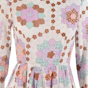 May include: A white dress with a floral print. The print features a patchwork design with brown, pink, purple, and blue flowers.