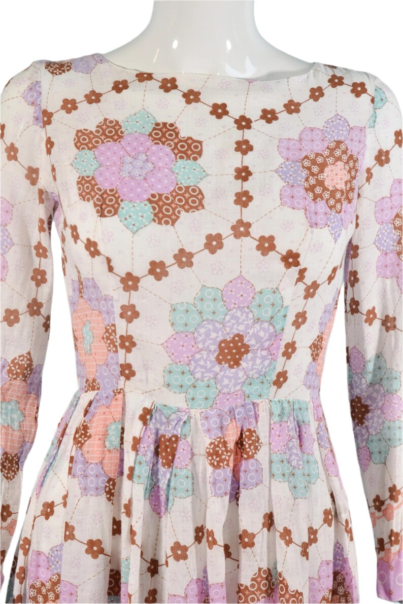 May include: A white dress with a floral print. The print features a patchwork design with brown, pink, purple, and blue flowers.