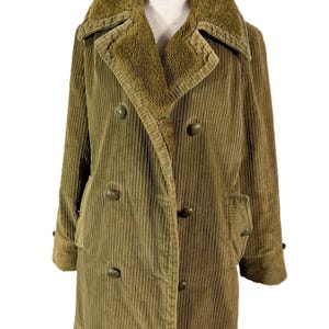 May include: A vintage olive green corduroy coat with a faux fur collar. The double-breasted coat features large, round buttons and two front pockets. The coat is displayed on a mannequin.