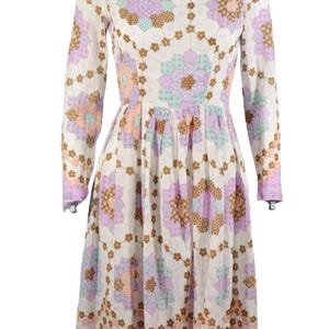 May include: A white dress with a floral pattern in shades of pink, purple, and brown. The dress has long sleeves and a fitted bodice. The skirt is full and flowing.