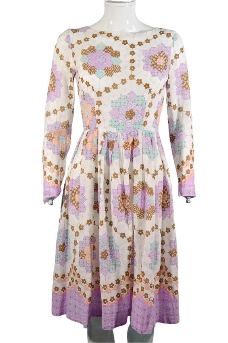 May include: A white dress with a floral pattern in shades of pink, purple, and brown. The dress has long sleeves and a fitted bodice. The skirt is full and flowing.