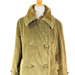 May include: A vintage olive green corduroy coat with a faux fur collar. The double-breasted coat features large, round buttons and two front pockets. The coat is displayed on a mannequin.