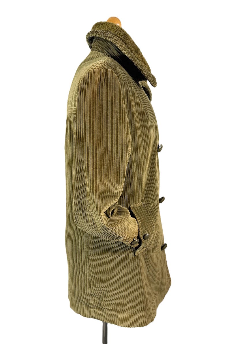 May include: Olive green corduroy coat with a plush collar. The coat features a button-up front, two pockets, and a classic design. The corduroy fabric has vertical ridges. A timeless outerwear piece.