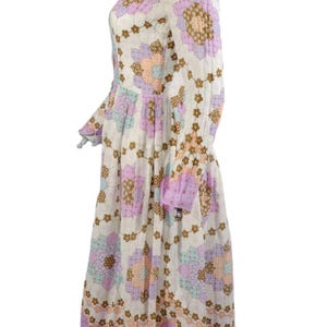 May include: A white midi dress with a floral print in shades of pink, brown, and blue. The dress has long sleeves and a gathered skirt.