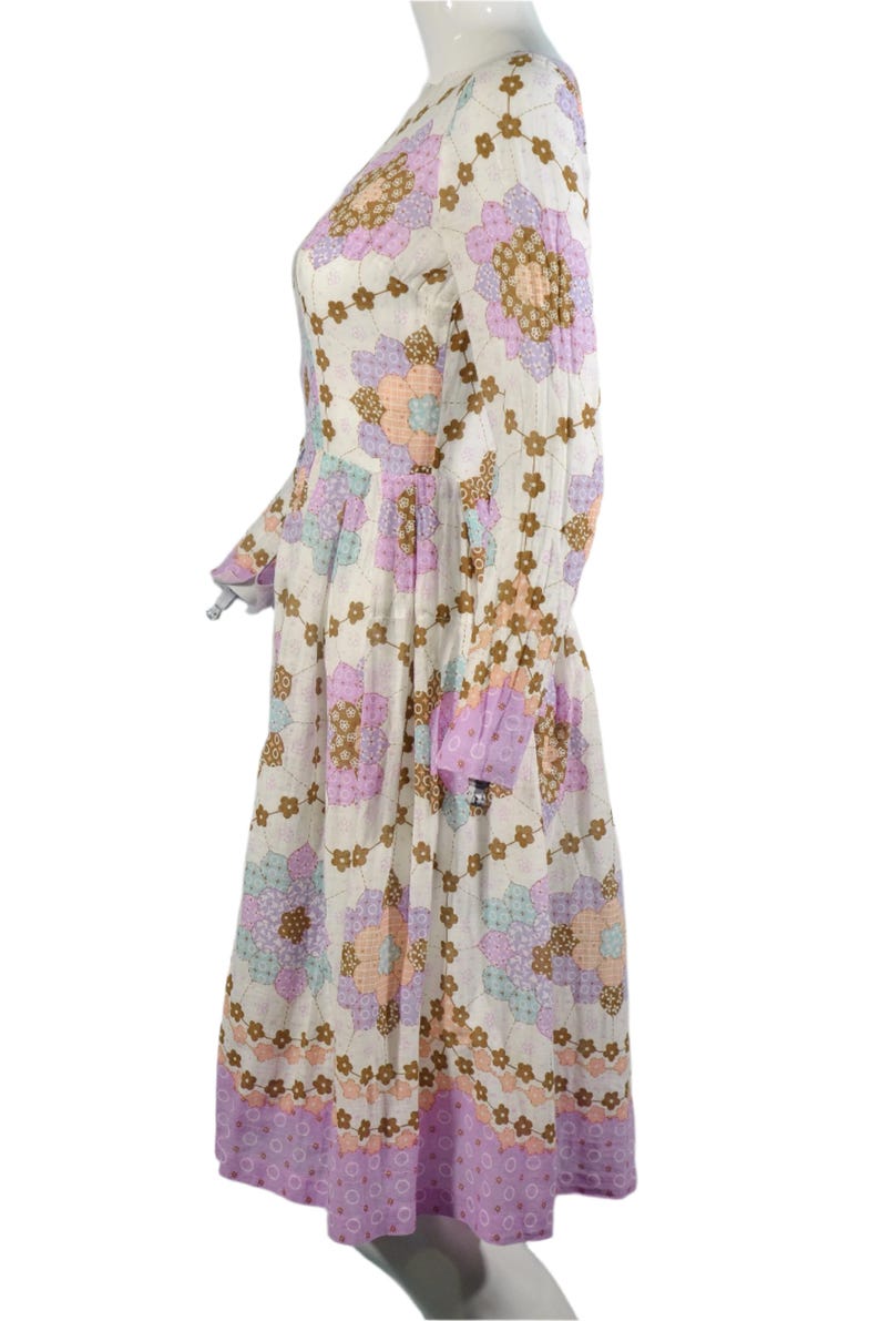 May include: A white midi dress with a floral print in shades of pink, brown, and blue. The dress has long sleeves and a gathered skirt.