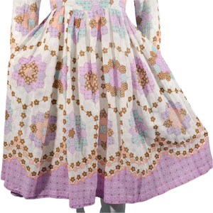 May include: A white dress with a floral print featuring a patchwork design of pink, brown, and blue flowers. The dress has a full skirt and long sleeves.