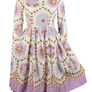 May include: A white dress with a floral print in shades of pink, brown, and blue. The dress has long sleeves and a fitted bodice with a full skirt.