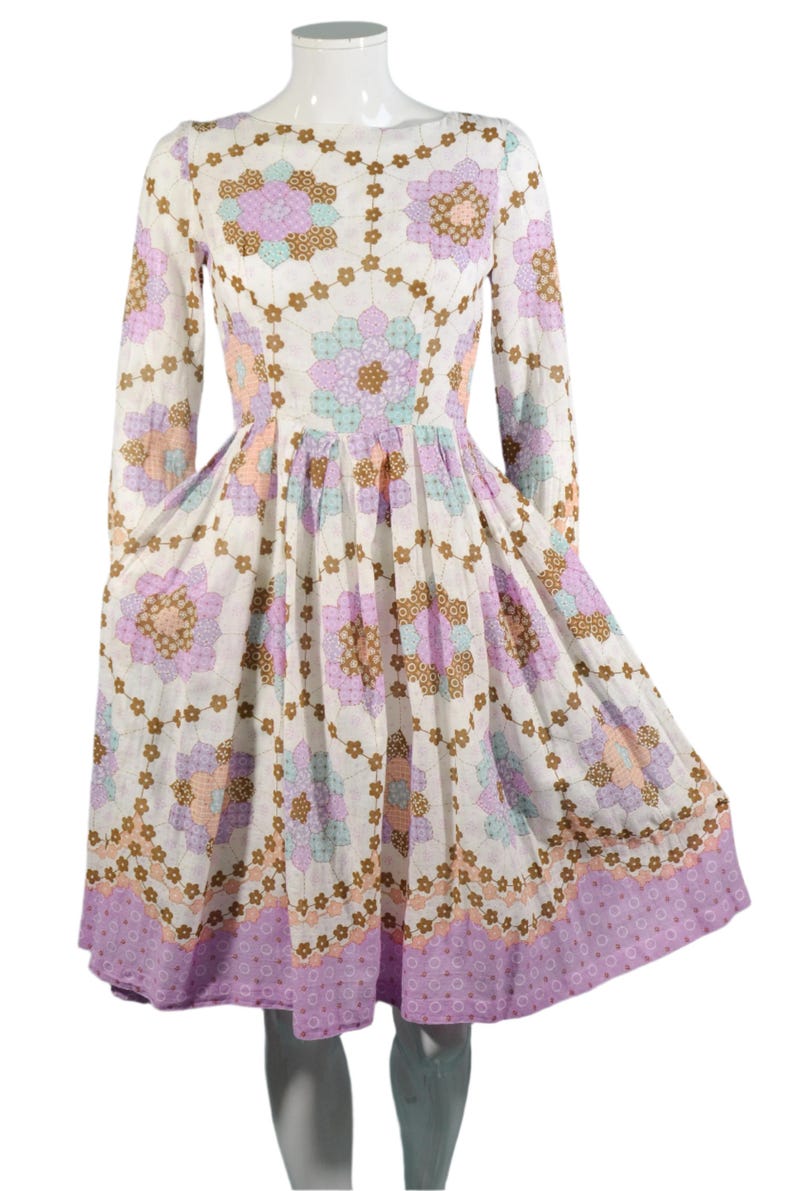 May include: A white dress with a floral print in shades of pink, brown, and blue. The dress has long sleeves and a fitted bodice with a full skirt.