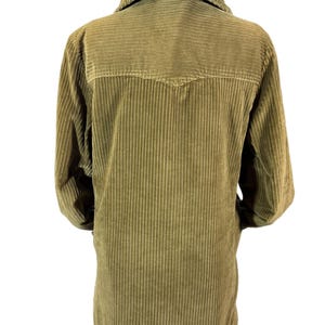 May include: Olive green corduroy jacket with a faux fur collar. The jacket has a button-up front and long sleeves. The back of the jacket is visible, showing vertical corduroy lines and a yoke detail. The jacket is displayed on a hanger.