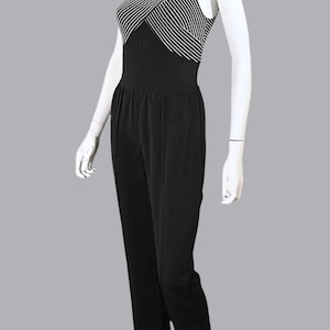 Puede incluir: Un mono sin mangas de rayas blancas y negras con cuello alto y cuerpo ajustado. El mono tiene pierna ancha y un ajuste holgado.