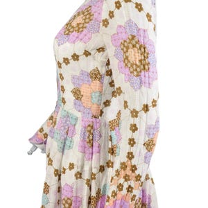 May include: A white dress with a floral print in shades of pink, purple, and brown. The dress has long sleeves and a fitted bodice.