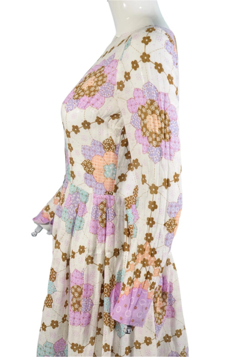 May include: A white dress with a floral print in shades of pink, purple, and brown. The dress has long sleeves and a fitted bodice.