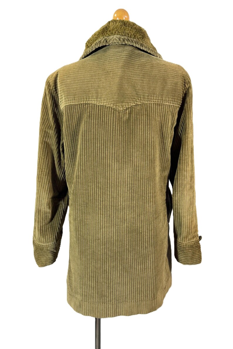 May include: A vintage olive green corduroy jacket with a faux fur collar. The jacket has a button closure, long sleeves, and a classic design. The corduroy fabric has vertical ridges. The jacket is displayed on a hanger.