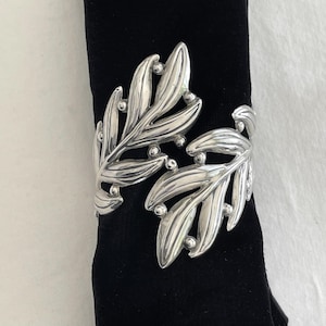 May include: Silver leaf-shaped bracelet with a textured finish and small round accents.