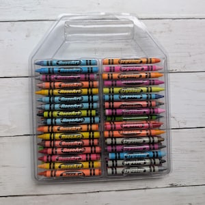 May include: A clear plastic container filled with rows of colourful crayons. Each crayon is labelled with the brand name "RoseArt". The crayons are in various colours, including blue, orange, pink, yellow, and green, and are arranged neatly.