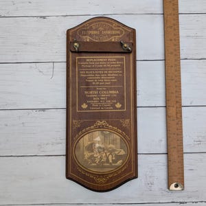 May include: A rectangular wooden wall plaque labeled Wireless Telephone Answering Machine with text regarding replacement pads from North Columbia Trading Company. A wooden ruler shows the item is approximately 12 inches in total length.