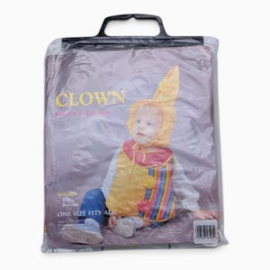 Puede incluir: Un conjunto de gorro y babero de payaso empaquetado en una bolsa de plástico transparente con asa negra. El empaque presenta el texto CLOWN Bonnet & Bib Sets, ONE SIZE FITS ALL e incluye un gráfico de un niño con un babero amarillo, rojo y a rayas.