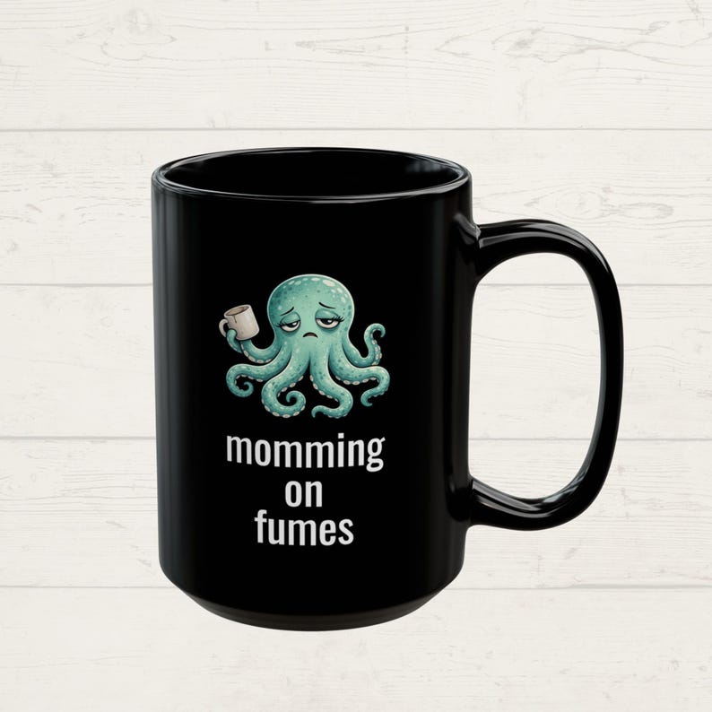 mug with exhausted cartoon octopus with an empty coffee mug featuring the phrase "momming on fumes".