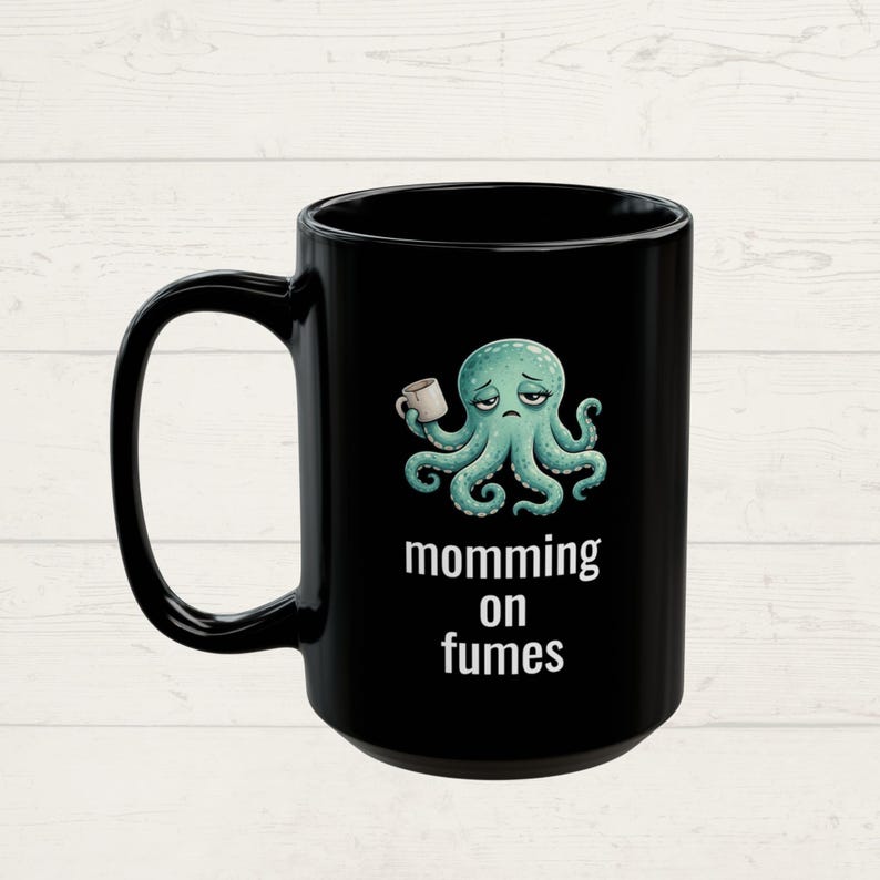 mug with exhausted cartoon octopus with an empty coffee mug featuring the phrase "momming on fumes".
