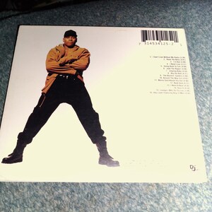 May include: A white CD back cover featuring a photograph of a person wearing a tan hooded jacket, black pants, and black boots with arms crossed. The cover includes a barcode, a tracklist numbered 1 through 16, and a small DJ logo in the corner.