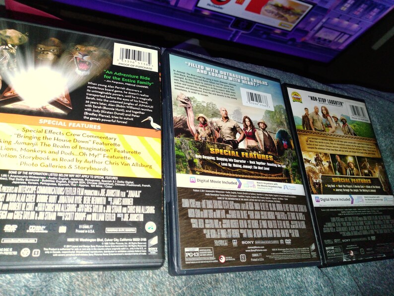 May include: Three DVD movie cases are displayed, showcasing the backs of the cases. The cases feature colorful graphics and text, with titles and special features listed. The cases are in good condition, suggesting they are well-preserved.