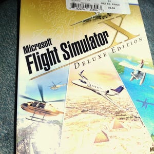 May include: Microsoft Flight Simulator X Deluxe Edition PC DVD game box. The cover features images of various aircraft, including helicopters and airplanes, set against a landscape with pyramids. The game's title is prominently displayed.