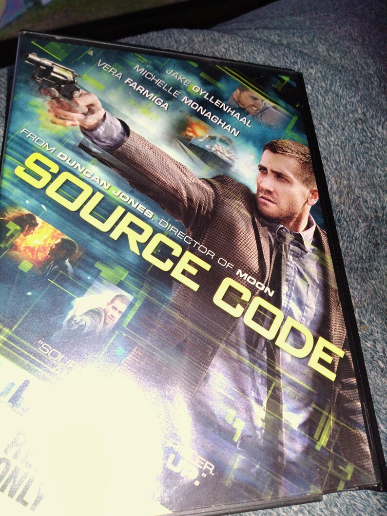 May include: DVD case for the movie "Source Code" featuring Jake Gyllenhaal. The cover art shows Gyllenhaal holding a gun, with the title in large yellow letters. Other actors listed include Vera Farmiga and Michelle Monaghan.