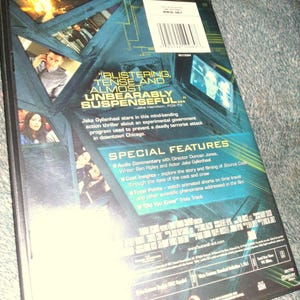 May include: A DVD case with a teal and black design, featuring images of actors and text. The back of the case includes quotes like "Blistering, tense and almost unbearably suspenseful." Special features are listed, including audio commentary and trivia.