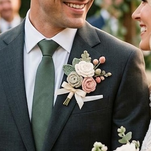 Puede incluir: Escena de boda con una pareja sonriente. El novio lleva un traje gris oscuro, corbata verde y un prendido floral. La novia sostiene un ramo de flores rosas y blancas.