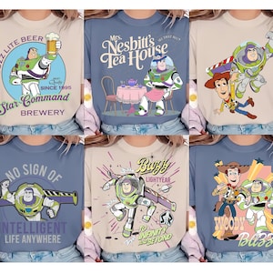 May include: A collection of six t-shirts featuring various graphic prints of Buzz Lightyear and Woody. The designs include text such as Buzz Lite Beer, Mrs. Nesbitt's Tea House, No Sign of Intelligent Life Anywhere, and To Infinity and Beyond.