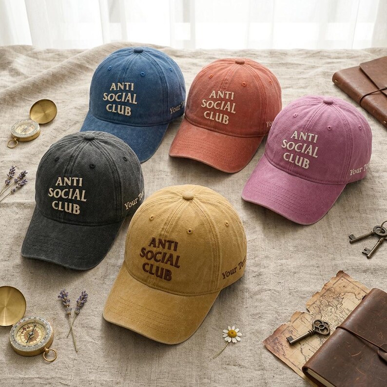 Peut inclure: Cinq casquettes de baseball de couleurs vari&eacute;es : bleu, rouge, violet, gris et beige. Chaque casquette porte l'inscription "ANTI SOCIAL CLUB" en blanc ou marron. Les casquettes sont dispos&eacute;es sur une surface neutre avec des &eacute;l&eacute;ments d&eacute;coratifs.