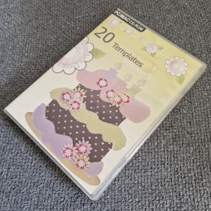 May include: A CD-ROM disc case with a yellow background and a colourful illustration of a cake with flowers. The text on the case reads "20 Templates Volume 3".