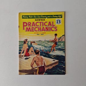 May include: A vintage magazine cover for Practical Mechanics, featuring a yellow background with the title "Practical Mechanics" in red and black lettering. The cover depicts a man water skiing on a lake with a woman and another man on a jetty in the background. The magazine is dated May 1957 and has the number 13 on the cover.