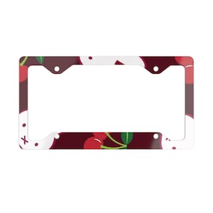 May include: A license plate frame with a cherry pattern. The frame has a white border and a dark red background with red cherries and green leaves. The frame has four mounting holes.