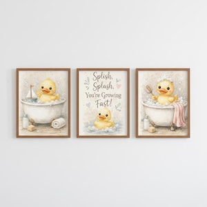 Puede incluir: Conjunto de tres láminas enmarcadas con ilustraciones en acuarela de un patito de goma amarillo. Una lámina muestra un pato en una bañera con un velero, otra con el texto "Splish, Splash, You're Growing Fast!", y la tercera con un pato en un baño de burbujas.