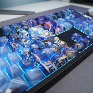 Pode incluir: Um teclado mecânico personalizado com teclas azuis e roxas. As teclas apresentam obras de arte em estilo anime e são retroiluminadas com LEDs azuis. O teclado tem uma moldura preta.