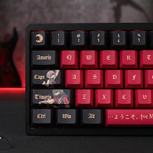 May include: Black and red mechanical keyboard with custom keycaps. The keycaps feature anime-style illustrations and text, including "Amorís", "Caps", and "Timoris". The keyboard has a black frame and a red base, with the text "...ようこそ。Ave M" on the spacebar.
