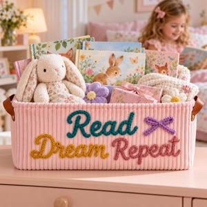 Individuell gestalteter Bücherkorb aus Cord mit gehäkelter Schleife und dem Aufdruck „Read Dream Repeat“, ideal als Leseorganizer für Mädchenzimmer und Geschenkset für kleine Leseratten.