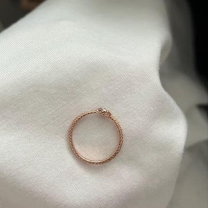 May include: A rose gold ring shaped like a coiled snake with a textured, scale-like surface. The ring features a small, detailed snake head at the top where the two ends meet, creating a continuous circular band design with a metallic finish.